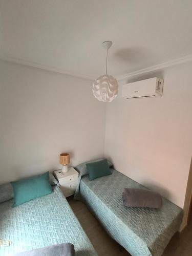 two beds in a small room with a lamp at Casa Trastévere in San Juan de los Terreros