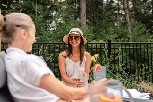a woman in a hat sitting at a table at Chalet White Rabbit au Lac Fiddler in Mille-Isles