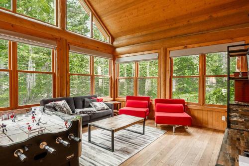 a living room with a couch and red chairs at Chalet White Rabbit au Lac Fiddler in Mille-Isles