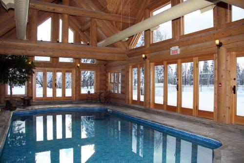 una piscina cubierta en una casa de madera con ventanas en Chalet White Rabbit au Lac Fiddler, en Mille-Isles
