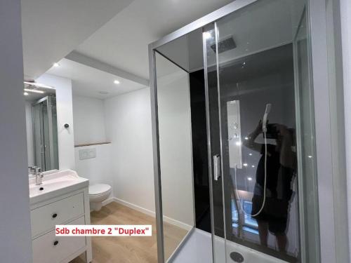 a person taking a picture in a glass shower in a bathroom at Duplex sympa Verviers in Verviers
