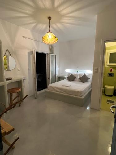 a white bedroom with a bed and a chandelier at Alexandra’s studios in Iraklia