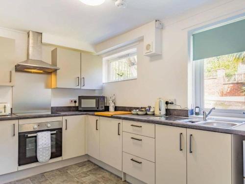 a kitchen with white cabinets and a sink and a window at Lovely Magnolia Accommodation 3king Torquay in Torquay