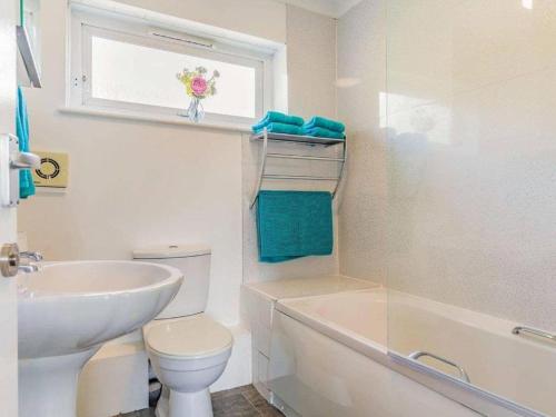 biała łazienka z umywalką, toaletą i oknem w obiekcie Lovely Magnolia Accommodation 3king Torquay w mieście Torquay