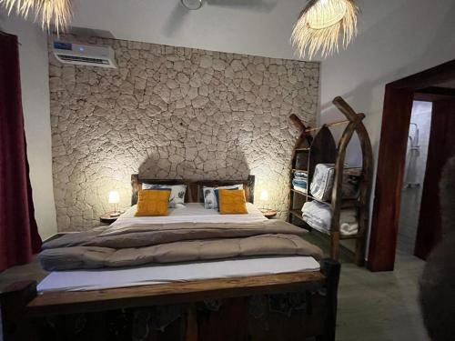 a bedroom with a large bed with a stone wall at Villa tangawizi kendwa in Kendwa