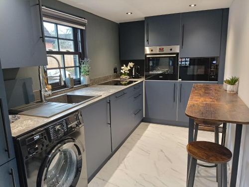 a kitchen with a washer and dryer and a table at Stansted Airport Cottage in Bishops Stortford