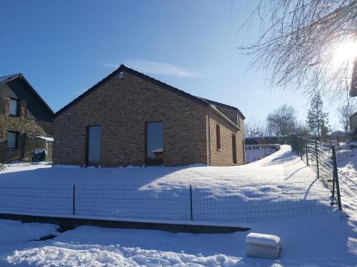 une maison en briques avec de la neige devant elle dans l'établissement Gîte rural "l'Anseromia", à Dinant