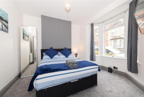 a bedroom with a bed with blue sheets and a window at Modern home near the hopsital in Exeter