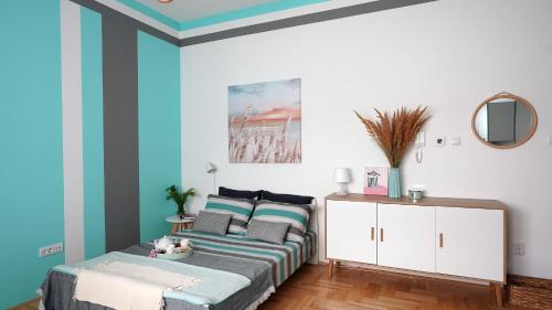 a bedroom with blue walls and a bed and a mirror at Tiffany Apartment in Novi Sad