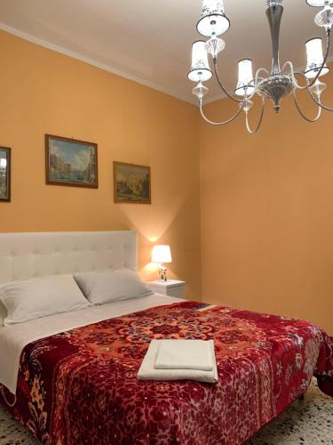a bedroom with a bed with a red blanket and a chandelier at PRINCIPE ROOMS in Rodigo