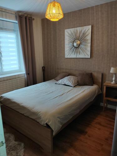 a bed in a bedroom with a chandelier at La maison des noyers in Parigné-lʼÉvêque