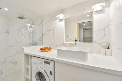 La salle de bains blanche est pourvue d'un lavabo et d'un lave-linge. dans l'établissement Duplex à Paris Saint-Ambroise, à Paris