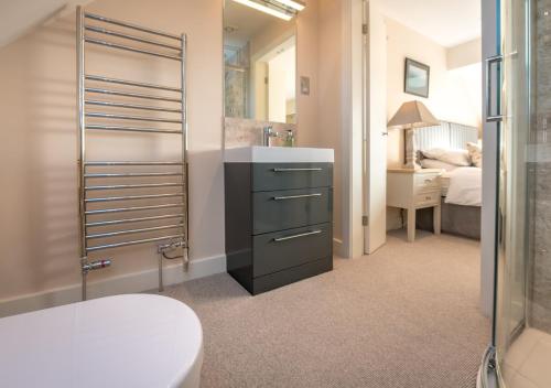 a bathroom with a sink and a toilet and a bedroom at The Summer House in Abersoch