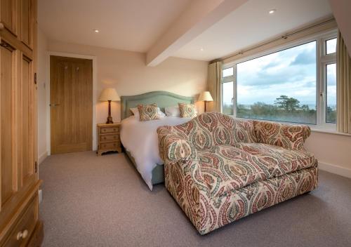 a bedroom with a bed and a couch and a window at The Summer House in Abersoch