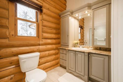 uma casa de banho com paredes de madeira, um WC e um lavatório. em Chalet Golden Bear - Fiddler Lake em Mille-Isles