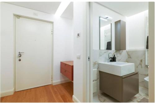 a white bathroom with a sink and a mirror at Porta Nuova Apartment in Milan