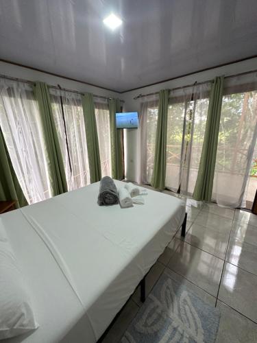 a bedroom with a large white bed with green curtains at CABAÑAS DEL LAGO / BUNGALOWS in San Ramón