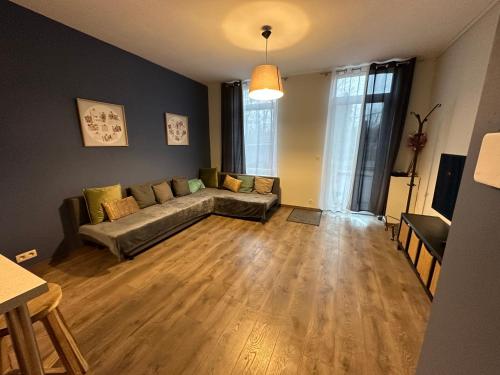 a living room with a couch and wooden floors at LFA Charmante maison de ville in Flémalle-Grande