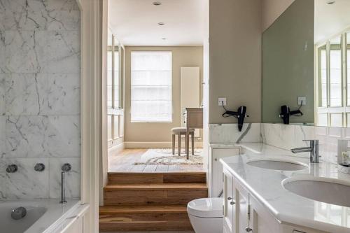 a white bathroom with two sinks and a toilet at A Grand Four Bedroom Townhouse at Knightsbridge in London