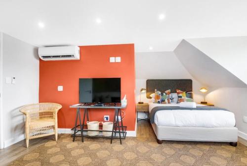 a bedroom with a bed with an orange accent wall at 30 on Whites Guesthouse in Bloemfontein