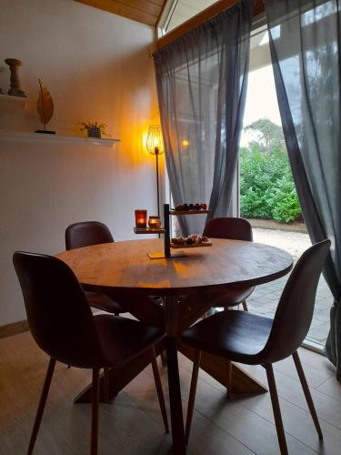 a dining room table with chairs and a window at Secret Wellness Droombos in Holten