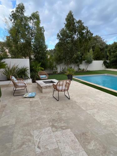 een patio met 2 stoelen en een zwembad bij Villa 6 personnes avec piscine in Istres