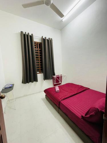 a bedroom with a red bed in a white room at Tok Mak Homestay Bukit Mertajam in Kubang Semang