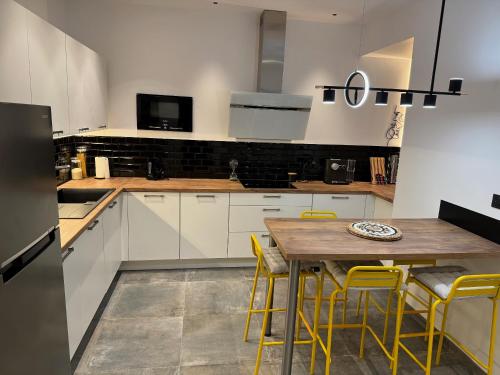 une cuisine avec une table en bois et des chaises jaunes dans l'établissement PitchMoon Bel Appartement 85 m2, grande terrasse extérieure, à Grasse