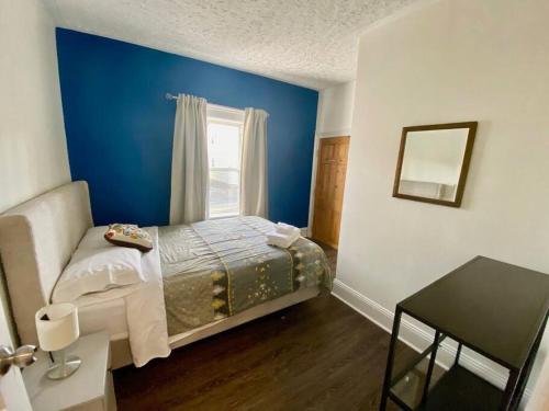a blue bedroom with a bed and a window at Large Townhouse, Lower Floor with AC, City Center in Halifax