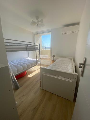 1 dormitorio con 2 literas y ventana en Appartement 100 m2 Terrasse Piscine, en Gruissan
