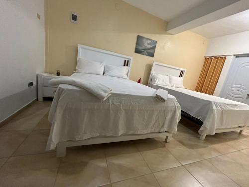 a bedroom with two beds with white sheets at Habitación doble Villa Marchena Azua in Azua de Compostela