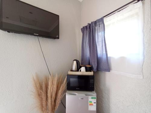 a flat screen tv hanging on a wall next to a window at OR Tambo Stay Unit 2 in Boksburg