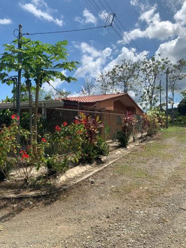 a house with a fence and flowers on the side of a road at Casa Heliconia in Puerto Jiménez