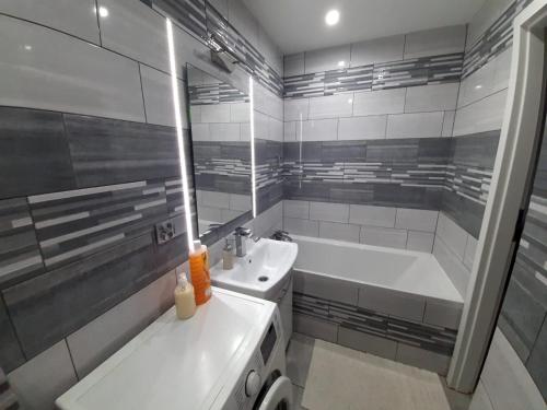 Baño blanco con bañera y lavamanos en Apartament Laurka, en Kamienna Góra