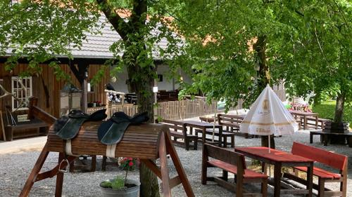 eine Gruppe von Picknicktischen und Bänken mit einem Regenschirm in der Unterkunft Forsthaus Schöntal in Aachen