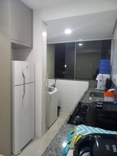 eine Küche mit einem weißen Kühlschrank und einem Herd in der Unterkunft Apt aconchegante com 2 quartos! j in Patos de Minas