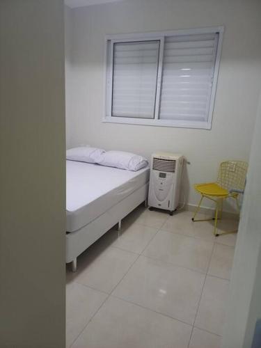 Habitación blanca con cama y ventana en Apt aconchegante com 2 quartos! j en Patos de Minas