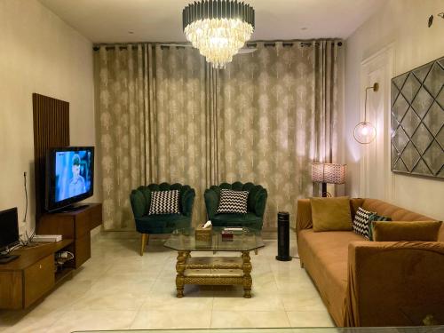a living room with a couch and two chairs and a television at Homey Stays - 3 Bedroom Holiday Home - DHA in Lahore