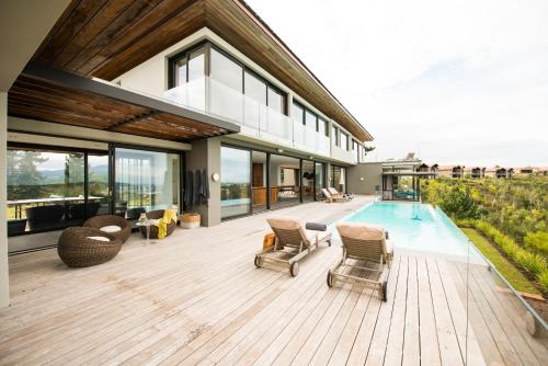 a house with a deck with chairs and a swimming pool at Collection Luxury Accomodation Simola House in Knysna