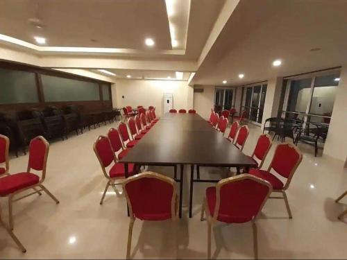 a conference room with a long table and red chairs at Kamal Farm Resort in Shenwa