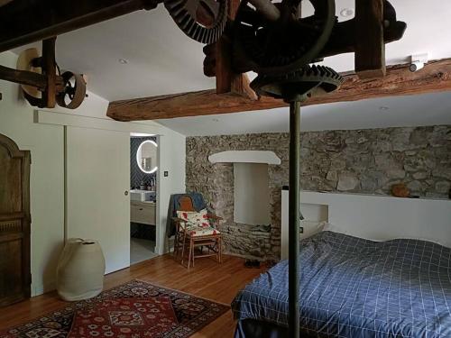 um quarto com uma cama azul e uma parede de pedra em Le Moulin de La Grave - Lagrasse em Lagrasse