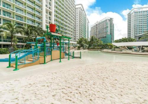 a playground in the middle of a beach with tall buildings at Azure Staycation in Manila