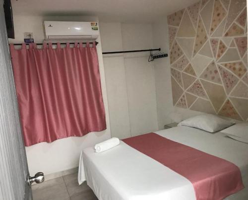 1 dormitorio con cama y cortina roja en Hotel URUMITA MAGICA, en Valledupar