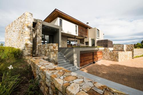 a home with a stone retaining wall and a house at Collection Luxury Accomodation Simola House in Knysna