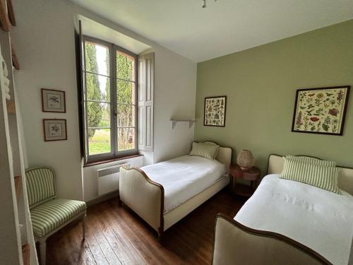 a bedroom with two beds and a chair and a window at Pavillon de Villefrancou in Montlaur