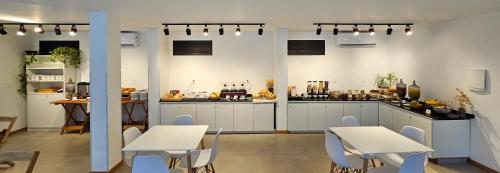 a kitchen with white tables and chairs and a counter at Verdes Pássaros Apart Hotel in Florianópolis