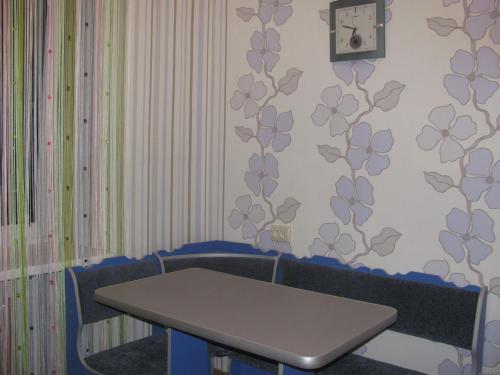 une table et des chaises dans une pièce avec une horloge murale dans l'établissement Bon Apart Avangard, à Mykolaïv