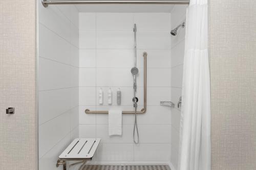 a shower with a bench and a shower curtain in a bathroom at Hampton Inn By Hilton Cornwall in Cornwall