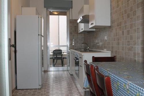 una cucina con frigorifero e tavolo con sedie di Casa dei Pini - Baia Verde a Gallipoli