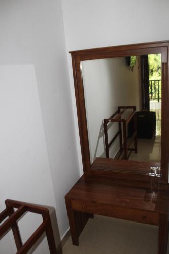 a mirror sitting next to a wooden table with a bench at UD Garden Hotel in Kataragama